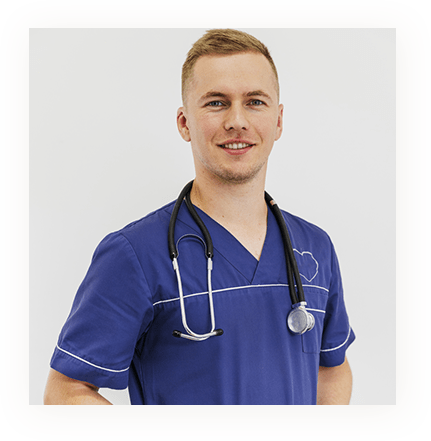 A male nurse in blue scrubs with a stethoscope smiling.
