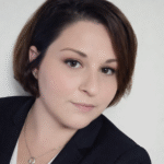 Professional headshot of a woman with short brown hair and a confident expression.