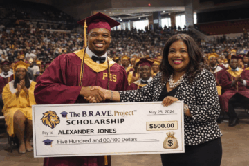 Graduate in cap and gown with scholarship check and woman beside him.