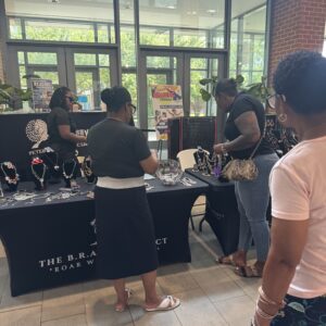 People interacting at a vendor booth inside a building.